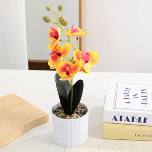 Artificial phalaenopsis bonsai detail shot, yellow and pink flower arrangement in white pot.