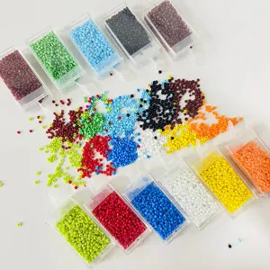 Close-up detail of colorful glass seed beads in small clear storage boxes, DIY jewelry making.