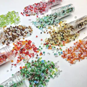 Detailed view of colorful glass seed beads spilling from transparent tubes for DIY jewelry.
