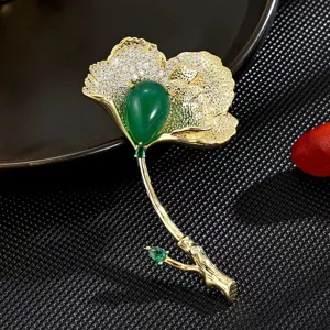 Vue de détail exquise de la broche feuille de ginkgo de luxe avec pierre précieuse verte et strass.