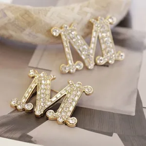 Elegante goldene M-Buchstaben Brosche mit Strass, hochwertiges Modeaccessoire für Damen.