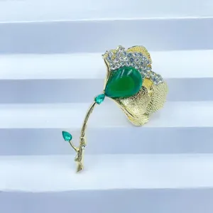 Détail de la broche élégante en forme de feuille de ginkgo avec pierre verte et strass.