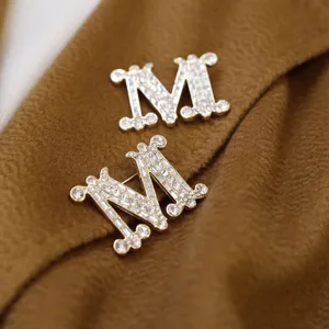 Detailaufnahme der glitzernden Strass M Brosche, elegantes goldenes Anstecknadel Detail.