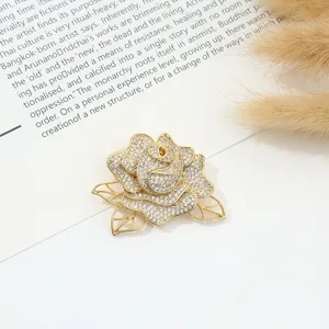 Elegant gold-tone rose brooch sparkling with clear rhinestones for women apparel and fashion accessory.