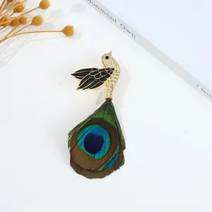 Close-up detail van vintage pauw vogel broche met goud metaal, zwart email en echte veer.