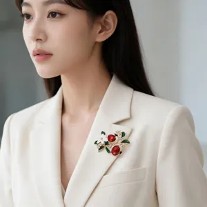 Close-up view of the elegant enamel pomegranate brooch worn on a chic beige blazer.