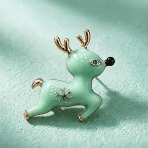 Gros plan d'une broche renne en émail vert menthe avec cristaux bleus et bords dorés.