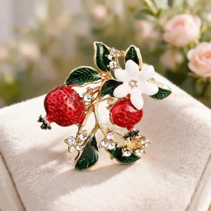 Close-up detail of the exquisite pomegranate flower brooch with vibrant enamel and sparkling crystals.