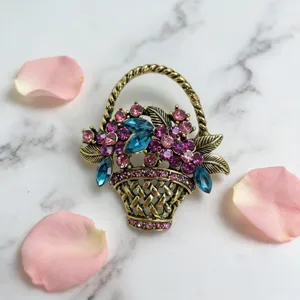 Vintage rhinestone flower basket brooch detail, antique gold metal pin with pink and blue crystals.