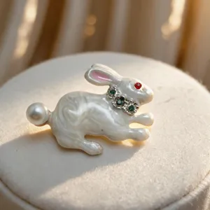 Primo piano dettagliato di una graziosa spilla con coniglio bianco, perla e strass brillanti.
