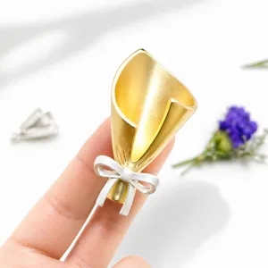 Exquisite metal bouquet brooch detail showing gold flower head and silver bow, stylish aesthetic.