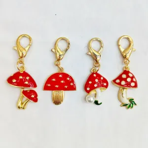 Pendentifs champignons métalliques rouges avec fermoirs homard dorés, détail charm sac émail.