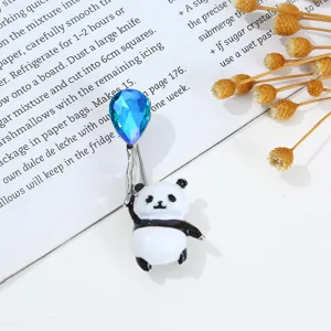 Primer plano de un lindo broche de panda con un globo de cristal azul y elegante diseño esmaltado.