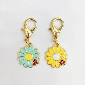 Vue détaillée des pendentifs marguerite colorée et coccinelle avec fermoir mousqueton.