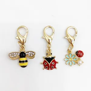 Gros plan de charmants pendentifs mousqueton en alliage émaillé abeille et coccinelle.