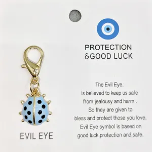 Détail du pendentif coccinelle en émail bleu avec fermoir mousqueton et carte de protection.