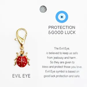Detail de pendentif charm coccinelle emaille rouge avec fermoir mousqueton sur carte.