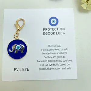 Vue détaillée du porte-clés éléphant mauvais œil en métal bleu avec carte de présentation.