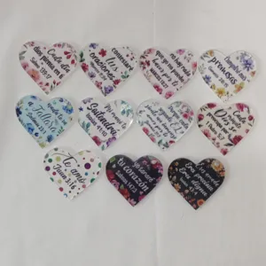 Detail view of heart shaped acrylic charms with Spanish Bible verse prints, DIY keychain parts.