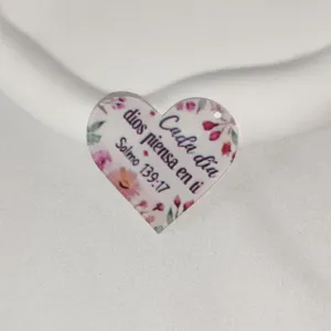 Detailed view of heart acrylic charm pendant featuring floral design and spanish quote.