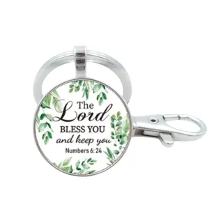 Zilveren metalen sleutelhanger met glazen hanger, groene bladeren en inspirerende religieuze tekst.