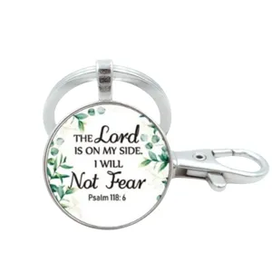 Zilverkleurige sleutelhanger met glazen cabochon, botanisch bladmotief en bijbelvers.