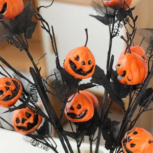 Ramo de ramas negras de Halloween con pequeñas calabazas naranjas para decoración.