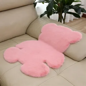 Close-up detail shot of the soft pink bear-shaped plush rug displayed on a beige leather sofa.