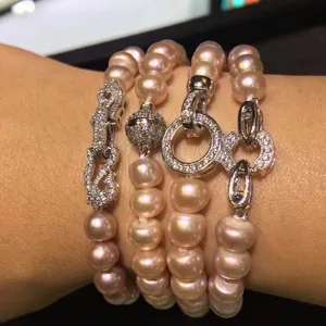 Close-up detail of multi-strand pink pearl bracelets with sparkling cubic zirconia magnetic clasps.