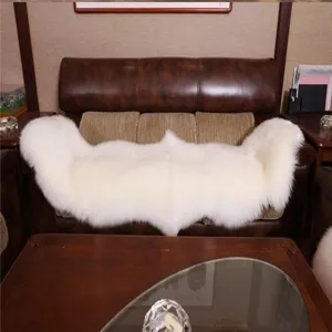 Detailed view of a soft fluffy white sheepskin sofa cushion placed on a dark leather couch.