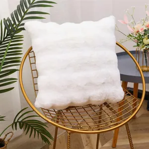 Detail view of the soft white faux rabbit fur throw pillow placed on a modern gold chair.