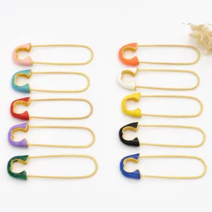 Close-up view of colorful enamel safety pins, gold-plated DIY jewelry findings and brooch materials.