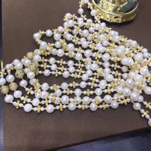 Detailed view of multi-strand pearl necklace featuring gold cross spacers and magnetic clasps.