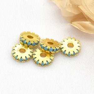 Close-up detail of gold-plated gear spacer beads with blue details for DIY jewelry making.