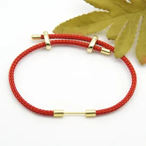 Detailed close-up of a red braided rope bracelet with golden metal components and adjustable slider.