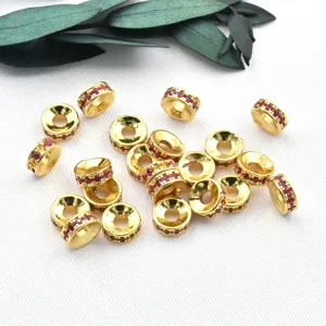 Close-up detail of 18k gold-plated round copper bead spacers with red micro-inlaid cubic zirconia.
