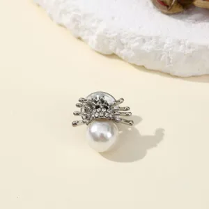 Close-up of delicate spider insect brooch with pearl and sparkling rhinestones for elegant outfits.