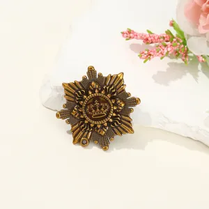 Dettaglio spilla sole in lega vintage, design corona retrò, elegante accessorio per abito elegante.