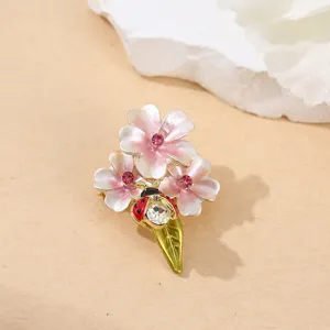 Nahaufnahme der exquisiten rosa Emaille Blumen Marienkäfer Brosche mit Strasssteinen.