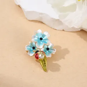 Detailaufnahme einer exquisiten blauen Emaille Blumen Brosche mit niedlichem Marienkäfer