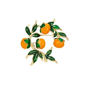 Gros plan detaille de la belle broche vintage en forme de branche de kaki emaillee orange et vert.