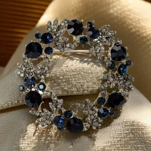 Dettaglio spilla a corona in cristallo blu brillante, elegante accessorio floreale per cappotti.