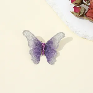 Detail view of a vintage embroidered butterfly brooch featuring purple and silver threads.