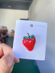 Close-up of cute red strawberry enamel brooch pin, detailed alloy craft for women fashion style.