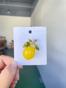 Detailed view of the enamel lemon brooch featuring vibrant yellow color and green leaves.