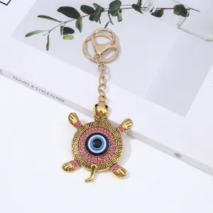 Evil eye turtle keychain with blue eye and pink rhinestones, stylish metal bag pendant.