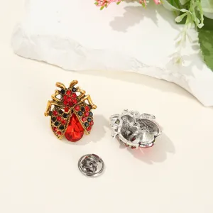 Detailed view of vintage ladybug brooch with red and black rhinestones and alloy metal.