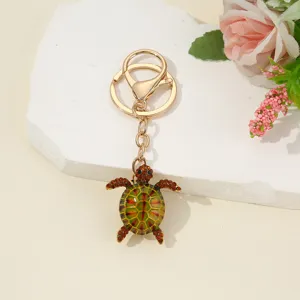 Close-up detail of a cute rhinestone turtle keychain pendant with gold metal clasp.