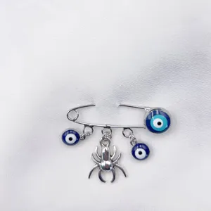 Silver safety pin brooch with evil eye blue beads and spider charm for women fashion.