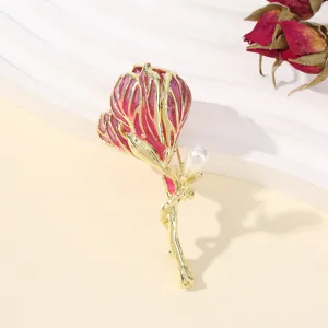 Gedetailleerd close-up van de prachtige vergulde roze geëmailleerde bloembroche met parel.